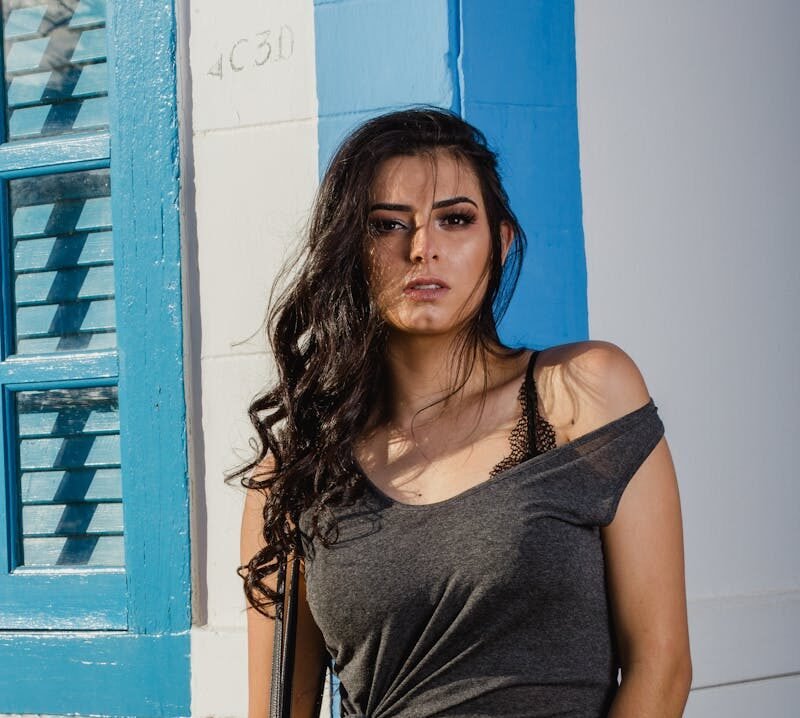 Woman in Grey Sleeveless Top Leaning on Wall